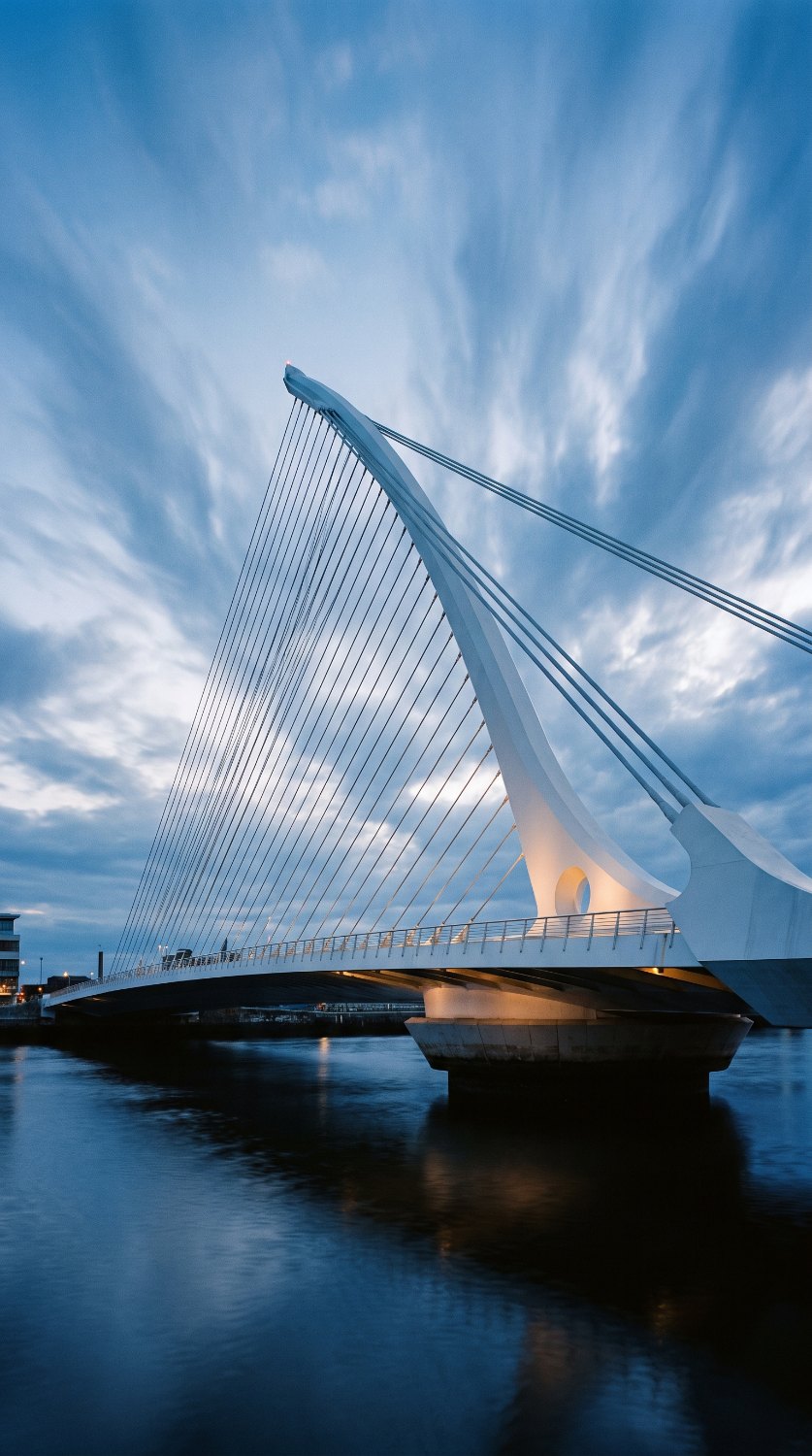 A cable-stayed bridge with a single inclined pylon at blue hour.